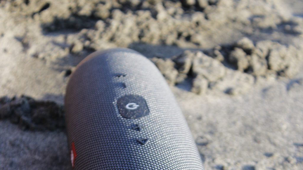 Caixa de som JBL portátil em ambiente externo na praia