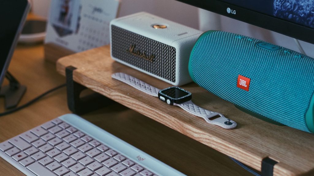 Caixa de som ao lado de notebook em mesa de trabalho