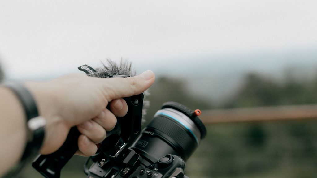 Fotógrafo segurando uma câmera DSLR em ambiente externo