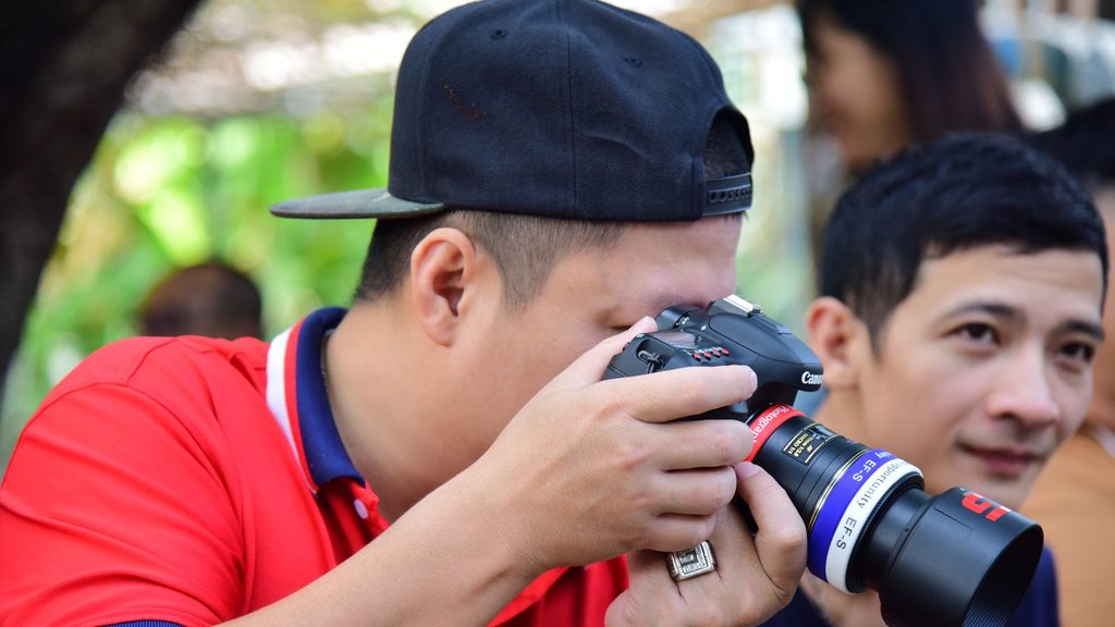 Pessoa segurando câmera DSLR em ambiente externo