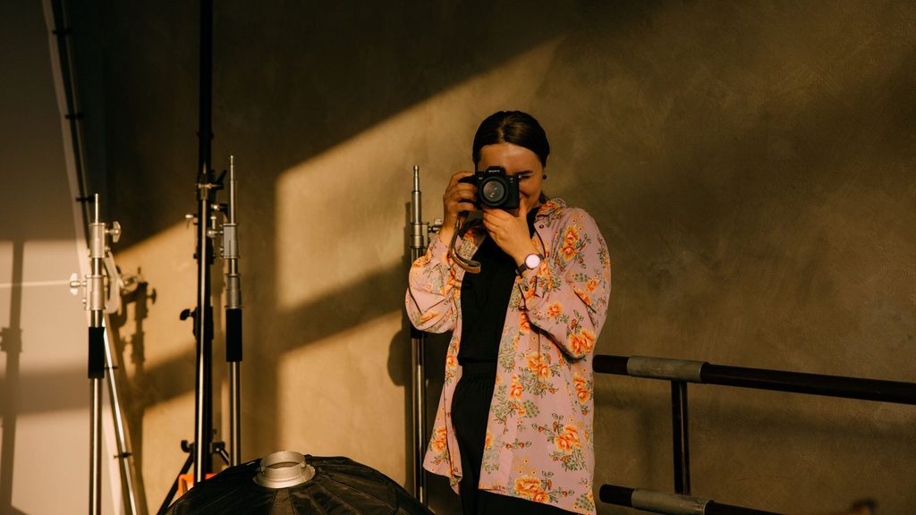 Pessoa gravando vídeo com câmera em estúdio iluminado
