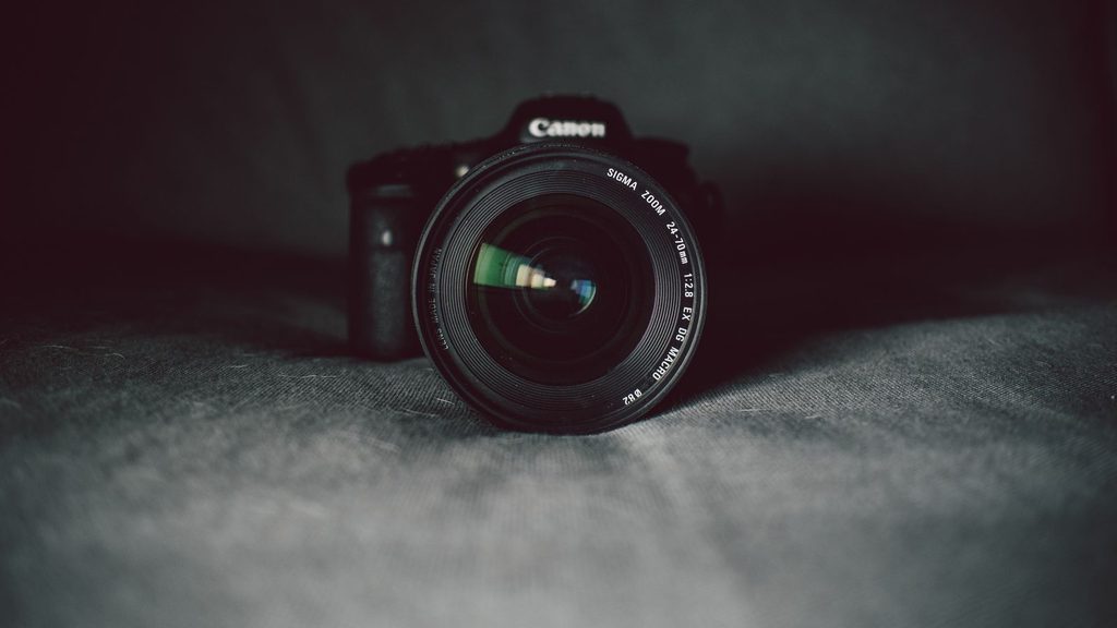 Câmera fotográfica digital ao lado de lentes sobre mesa
